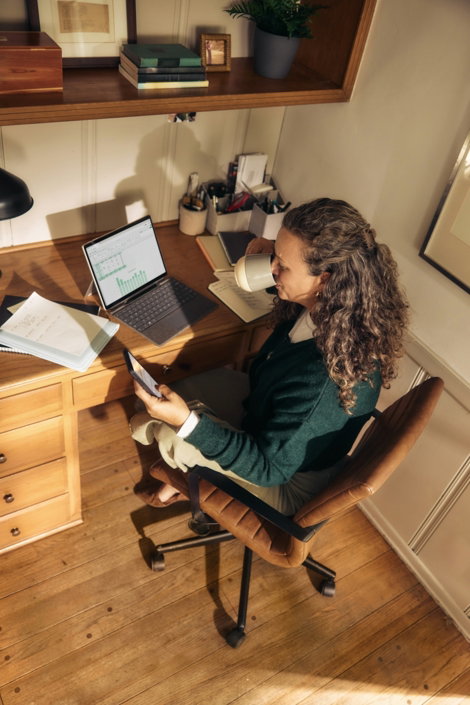 woman-working-at-a-desk-with-laptop-and-tablet-.jpg Woman working at a desk with laptop and tablet.